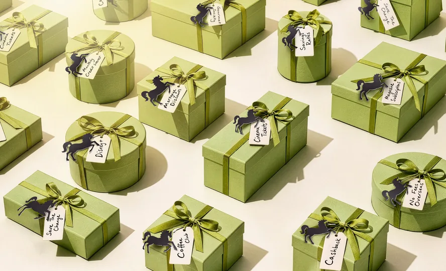 Rows of sage-green gift boxes tied with ribbon, each with a black Lloyds horse and a handwritten perk tag
