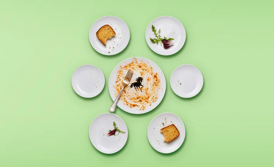 Plates of finished food on green, the black horse left on the middle plate