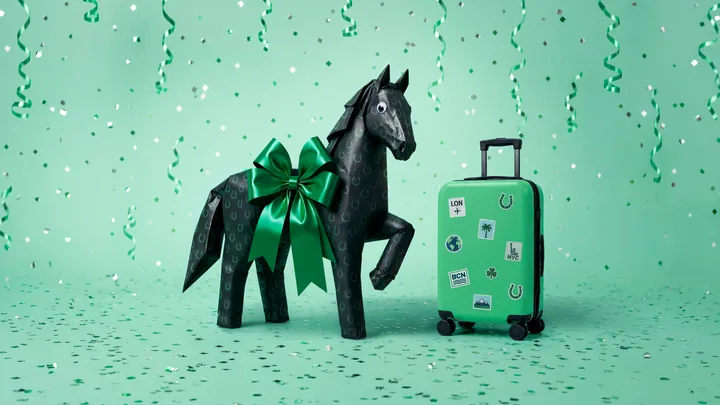 The wrapped black horse beside a green suitcase covered in travel stickers