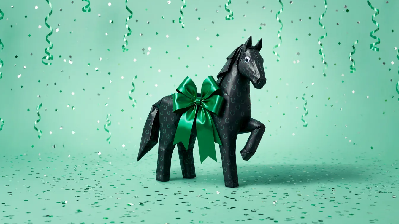 The Lloyds black horse, folded from black wrapping paper with a green satin bow, standing in a shower of green streamers and confetti