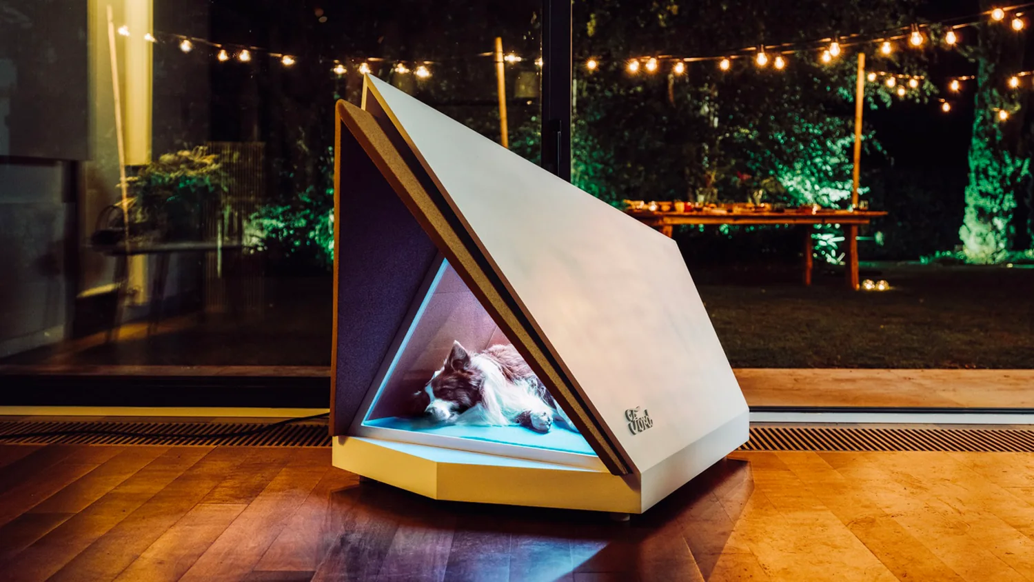 Ford's noise-cancelling kennel: a sleeping dog inside a sleek angular kennel on a patio at night